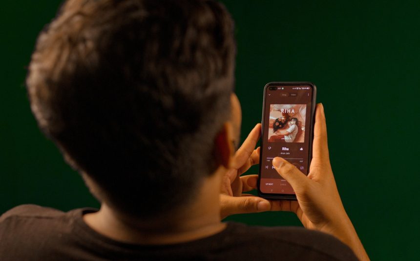 Pessoa usando um smartphone para ouvir música em um aplicativo de streaming.