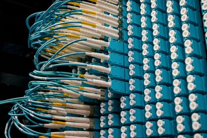 Cabos de fibra óptica conectados a um painel azul em um data center.