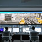 Profissionais monitoram sistemas e painéis digitais em uma moderna central de controle.