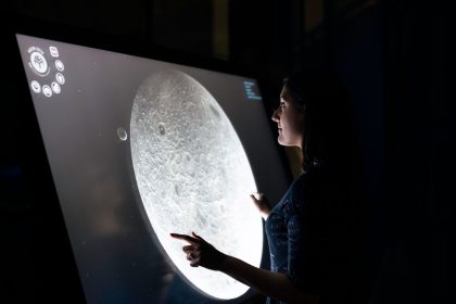 Mulher interage com uma tela que exibe detalhes da superfície da Lua.