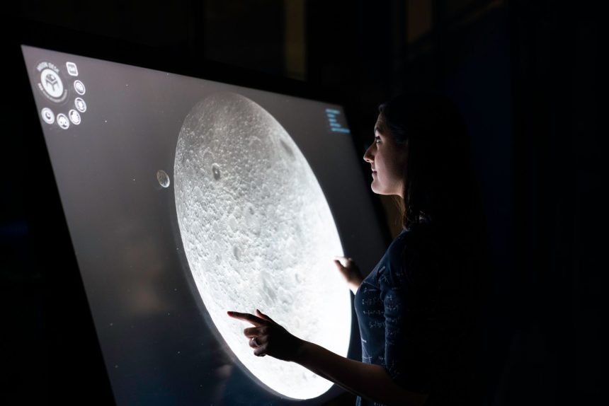Mulher interage com uma tela que exibe detalhes da superfície da Lua.