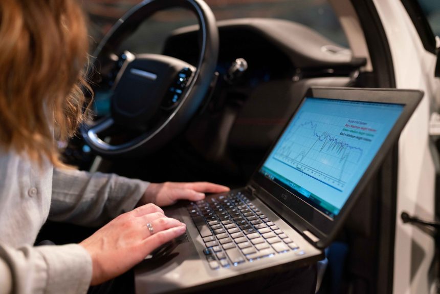 Engenheira usa um laptop para analisar dados de um veículo durante um teste técnico.