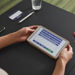 Pessoa usando um tablet em uma estação de atendimento eleitoral.