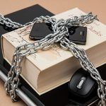 Computador portátil e smartphone representados em um conceito visual de restrição e segurança digital.