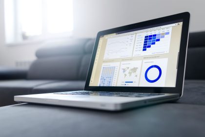 Notebook exibindo gráficos e painéis de análise de dados sobre uma mesa em ambiente de escritório.